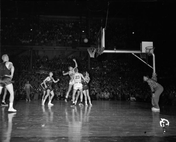 Action photograph of the Wisconsin-Minnesota basketball game at the U.W. Madison Fieldhouse. Wisconsin players are Fred Schneider (40) and Don Rehfeldt (23). Minnesota players are Jerry Mitchell and Whitey Skoog.