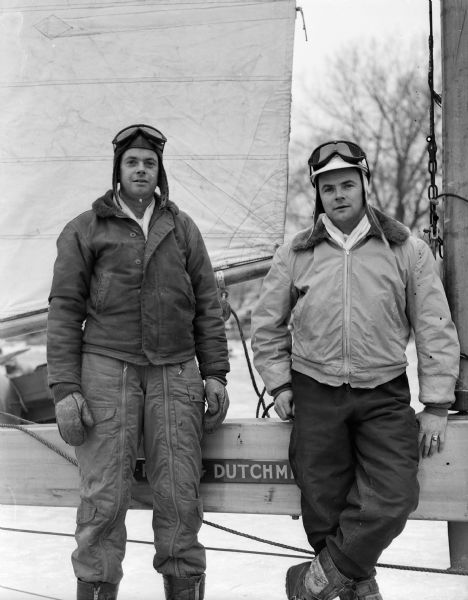 Two iceboat racers from Oshkosh, Chuck Nevitt and Jimmy Payton, standing by their iceboat during the Hearst Trophy Race on Lake Monona.