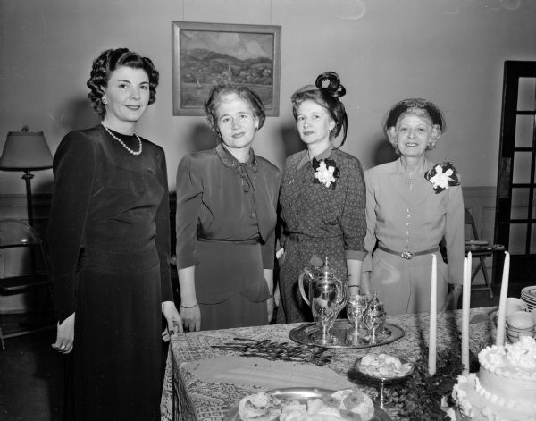 Four members of the Who's New Club gather around a table at the fifteenth anniversary tea at the YWCA. The social organization was established to provide a means whereby new women residents of Madison might make friends. From left to right are Mrs. Robert (Marjorie) Smith, Mrs. C.A. (Viola) Copp,  Mrs. C.M. Grise, and Mrs. T.M. (Ida) Sprowls.