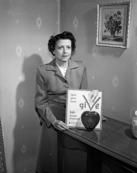 Mrs. James B. (Anya) Castle, chair of the women's division of the Madison Heart Fund Drive, displays a fundraising poster.