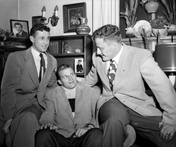 Co-Captain Jim Martin, the All-American tackle at Notre Dame last fall, is relaxing at the home of Dr. Stuart McCormick just after he arrived in Madison. Martin is with two former Wisconsin football stars while awaiting dinner. They are Tom Bennett, left, and Joe Kelly, right. 
Martin was here to narrate the movies showing highlights of Notre Dame's 1949 football season, which was part of the program by the Edgewood Athletic Association. Bennett, former Badger end and Big 10 pole vault champion, now is assistant coach at Edgewood. Kelly played center at Wisconsin for three years and was famed for his rugged line backing.