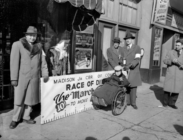 The winner of the March of Dimes Wheelchair race, in a close contest, is five-year-old Danny Maffet, son of Mr. and Mrs. David (Elizabeth) Maffett, 102 South Mills Street. Appearing in the photograph with Danny, from left to right: Hank Gempler, Mrs. Maffett, Harold Scale, and Warren Stopler. The event is sponsored by the Junior Chamber of Commerce.