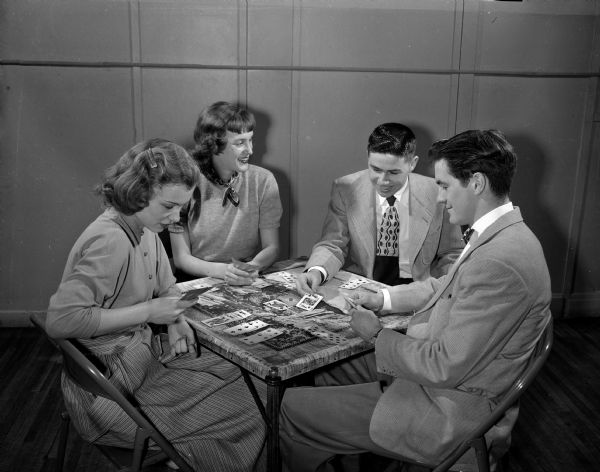 Four youth play canasta at the anniversary dance at the Loft Community Center, 16 East Doty Street. From left are: Mary Rose Gallagher, Ruth Leuthner, Dick Brilliott, and Bob Carpenter.
