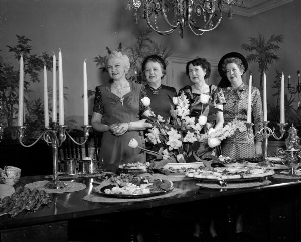 Mrs. Oscar Rennebohm (left), Mrs. Oscar Toebaas, Mrs. H. Lewis Greene, and Mrs. Foster Blackburn admire the twin silver candelabras which the Dane County Women's Republican club presented as a gift to the new executive mansion. More than 400 Republican women and their guests attended the party at the new mansion at 101 Cambridge Road in Maple Bluff.