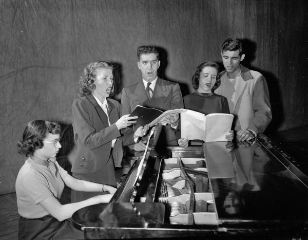 Finalists in tryouts for leading roles in the first opera ever to be presented by the Wisconsin Players are shown here with Doris Kassel, accompanist, at auditions held in the Wisconsin Union theater this week. The singers are, left to right: Harriet Borger, Reuben Dalbec, Jane Bandy, and Robert Harks. They were being auditioned for "The Telephone", an opera by Gian-Carlo Menotti to be presented in cooperation with the University of Wisconsin music school.