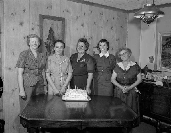 Members of the Hillcrest Homemakers club standing around a cake on a table while celebrating their 10th anniversary. Left to Right: Drake, Toepplelman, Dietz, Schaefer, MacLean.