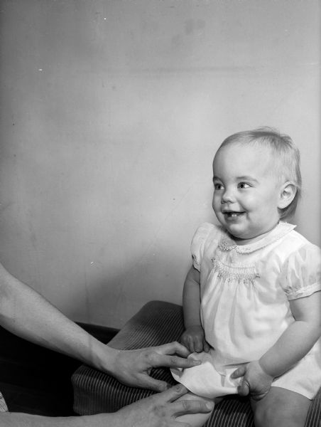 One-year-old Lisa Falligant, daughter of Mr. and Mrs. Louis A. Falliganat of Middleton Road, sitting on a cushion for a portrait. Lisa is one of five babies born February 14, 1949 and pictured in a valentine feature published in the <i>Wisconsin State Journal</i>.