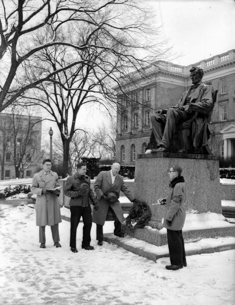 Rev. O.B. Ransopher of Wisconsin Rapids, president of the Lincoln Fellowship of Wisconsin, placed a wreath at the foot of the Abraham Lincoln statue in front of Bascom Hall on the University of Wisconsin campus to symbolize the "respect of admirers of Lincoln."  Left to right are: Robert Speaker, University student from Kenosha; Charles Norwald, president of Alpha Phi Omega, scouting fraternity; Ransopher; and John Brissee, Madison, member of the fraternity and official bugler at the ceremony.