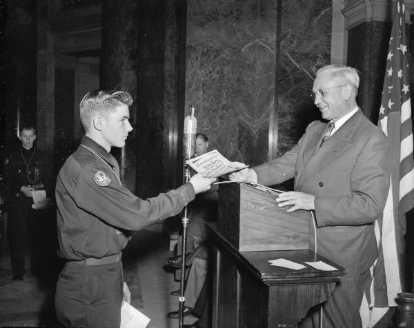Governor Rennebohm (right) is shown receiving an official invitation to the 1950 National Boy Scout Jamboree.  Explorer Scout Richard Kessenich of DeForest presents the invitation to the jamboree, which was held in Valley Forge, Pa.
