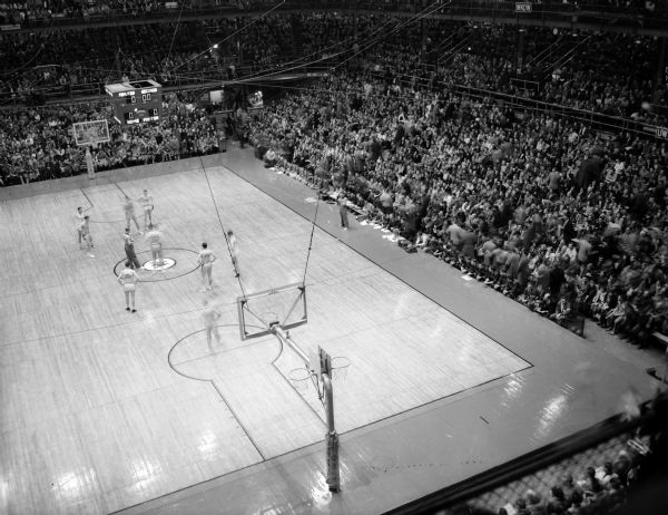 One image from an elevated panoramic view of University of Wisconsin-Madison Field House crowd at the Wisconsin vs. Iowa basketball game. Image published in newspaper is composite of three negatives.
