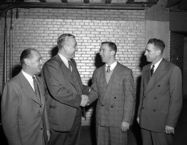 University of Wisconsin football star Captain Robert "Red" Wilson is recognized as the Big Ten Conference "Most Valuable Player" for 1949 and awarded the Chicago Tribune trophy. In the photograph are, from left, Harry Stuhldreher, University of Wisconsin athletic director; Wilfred Smith, Chicago Tribune sports writer; Wilson; and Badger head coach, Ivan Williamson.