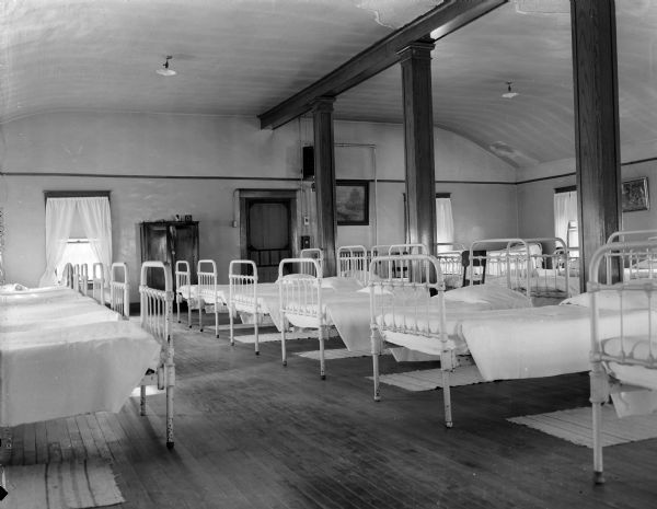 Three rows of beds on the third floor of the Dane County Home For The Aged. The room had only one exit leading to a wooden porch and a wooden fire escape. The newspaper called the building a "fire trap."