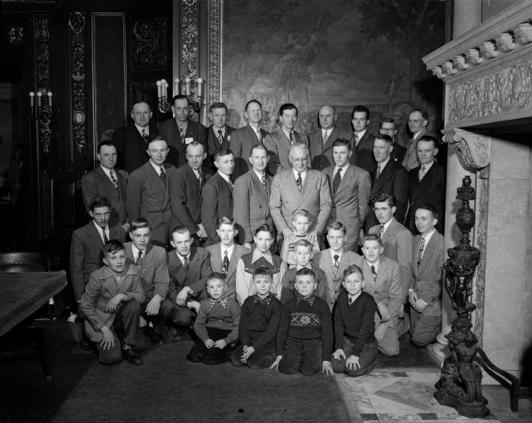Group portrait of fathers and sons with Governor Oscar Rennebohm in the governor's reception room of the Wisconsin State Capitol. Farm families from eleven counties were guests of the Madison Business Association for the first annual Farm Family Day.