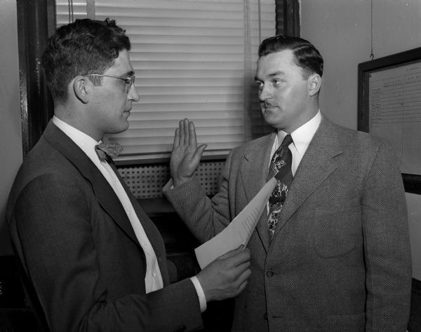 Russell W. Klitzman raises his right hand as he is sworn in as the first director of the Dane County Traffic Police by Dane County Clerk Keith Schwartz.  He retired in 1974.