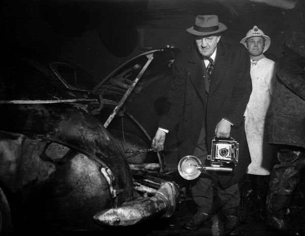 State Journal photographer Arthur M. Vinje, camera in hand, arrives at the scene of the fire at the Pyramid Motor Company, 434 West Gilman Street, to take pictures only to discover that it was the gasoline tank of his car that exploded in the fire. The explosion shattered a downstairs window and rocked adjacent buildings and injured seven employees.
Note: Photograph of Mr. Vinje taken by June Dieckmann, State Journal reporter who accompanied Mr. Vinje to the fire.