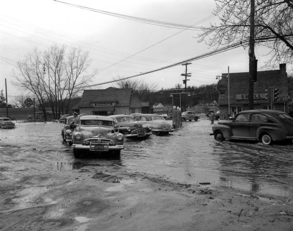 Flooding along University Avenue at Shorewood Boulevard. Businesses in the photograph include Frenchy's Restaurant, 3302 University Avenue, and the Walter Brooks Shell Service Station, 3300 University Avenue.