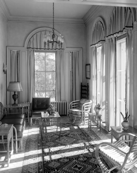 Sun streams into the first floor porch and garden room of the Governor's residence at 101 Cambridge Road. Its color is repeated in the warm golds of the tile floor. The furniture is sturdy and its upholstery sun proof.