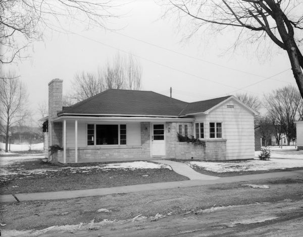 An exterior view of the home of Mr. and Mrs. Clarence Scholl on East Monroe Street. The ranch style house is an attractive combination of Lannon stone and white wood siding.