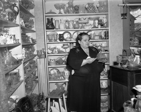 Antique dealer Helena Greenheck, Highway 130, standing in front of a collection of glassware.