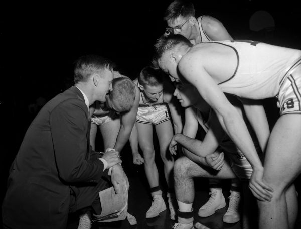 Members of a high school basketball team gather around their coach along the sideline of the University of Wisconsin fieldhouse during the state high school basketball tournament.