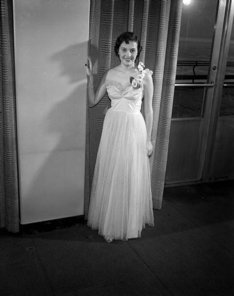 Joan Ellis, Delta Gamma, of Madison, Wisconsin is standing near a wall for a portrait while wearing a formal gown. Ellis was a member of the Court of Honor for the University of Wisconsin military ball.