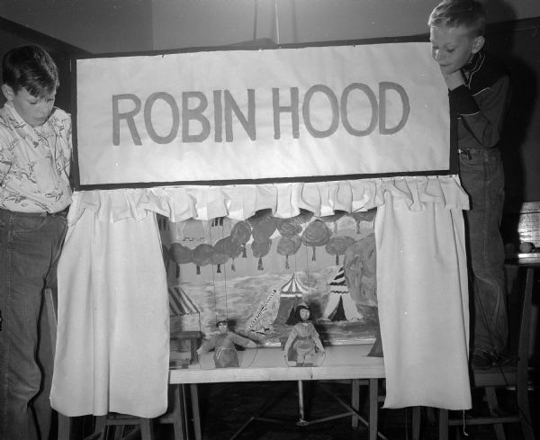 Students in the sixth grade classroom of teacher Freda A. Ferber check on their puppet's "stage presence" for the production of their puppet show, "Robin Hood". At left of the stage is Tommy Thompson, son of Mr. and Mrs. Thomas O. (Inez) Thompson, 425 Rogers Street, and Orville Rhoden, son of Mrs. Glady Roden, 32327 Sommers Avenue, at right.