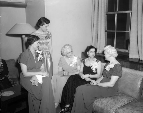 Five women chatting informally before the annual Matrix Banquet at Memorial Union. They are, left to right: Mrs. Lyman Dunn, Chicago, national president of Theta Sigma Phi; Betty Hansche, president of the UW chapter; Prof. Helen Patterson, chapter adviser; Lisa Sergio, the guest speaker, and Mrs. Oscar Rennebohm, wife of the governor. The 20th Annual Matrix dinner was sponsored by Theta Sigma Phi, a honorary and professional journalism sorority. The speaker, Lisa Sergio was an Italian-born journalist who fled fascist Mussolini's Italy to become an American citizen. She called on America to use its selling genius to "sell" democracy abroad.