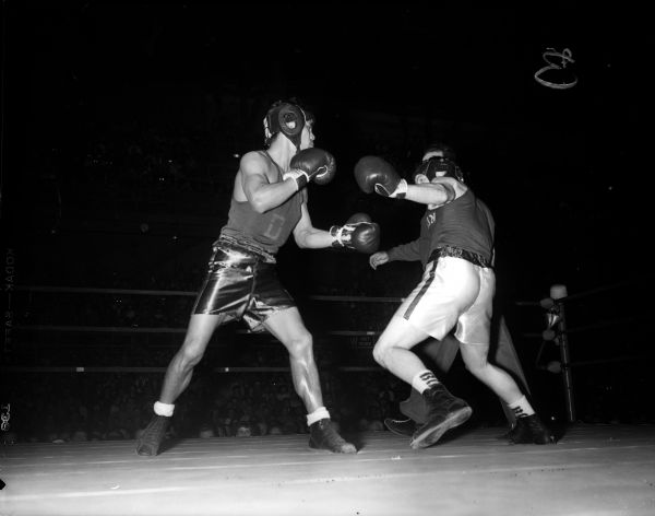 James "Red" Sreenan of the University of Wisconsin, right, leans back to ward off advance of Dave Miyagawa of DePaul during the Friday night fights at the University of Wisconsin fieldhouse.