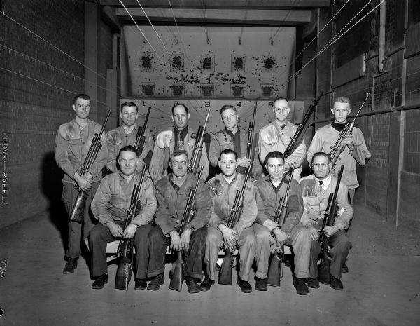 Group portrait of the 1949-1950 Southwest Wisconsin Champion Mount Horeb Rifle Club. The team was victorious in 12 straight matches with a score of 973 out of 1000.

Back row: Sgt. Jim Bruhy, G, Bohn, R. Wallace, M. Severson, Rev. Hector Gunderson, and R. Grinde. Front row: Ted Church, Forrest "Pops" Henderson, Russ Pope, C. Standorf, and Dr. Claude Reading. Jerry Moen, A. Anderson, and A. Soper were absent when the photo was taken.