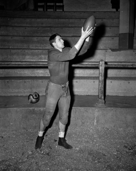 Bill Jenke of Hillsboro catches a football while standing in a stadium.  He is a freshman end on the University of Wisconsin football team.