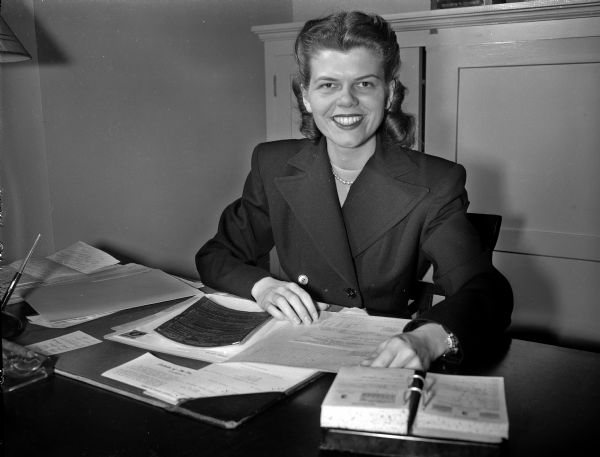 Grace H. Douma, assistant to Dean of Women at University of Wisconsin, sits at her desk in an office.