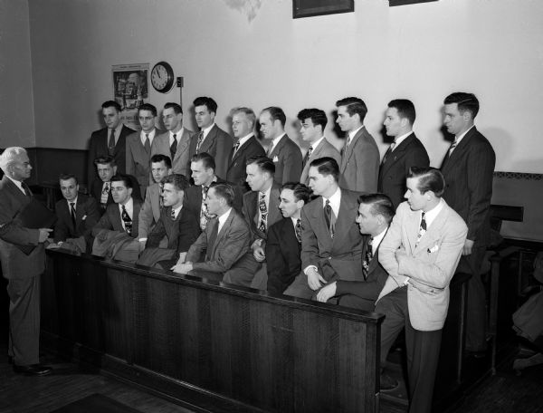 Superior Judge Roy H. Proctor explains the procedure of his court to Madison's 22 new police officers that will go on duty July 1, 1950. New police officers front row left to right: Thomas E. Runstrom, Karl H. Borland, John J. Fields, Kenneth M. Buss, Morris E. Jasper, Donald P. Uselmann, Charles E. Campbell, D. W. Michler, Ralin L. Phillips, Robert L. Graves, Robert Olson, and David G. Pope. Back row left to right: William J. Watry, Alfred A. Knorr, Francis J. Trapp, Boyd A. Dalton, Russell O. Runey, Charles E. Fess, Jr., Robert R. Newman, Earl E. Schuster, and Kirby E. Harless,
