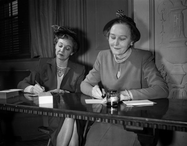 Two members of the Madison Art Association spring banquet committee write out invitations to the banquet. Left, Mrs. Thomas R. (Madeline)  Hefty, Edgewater Hotel, and right, Mrs. Dennison B. Cowles of 445 West Wilson Street.