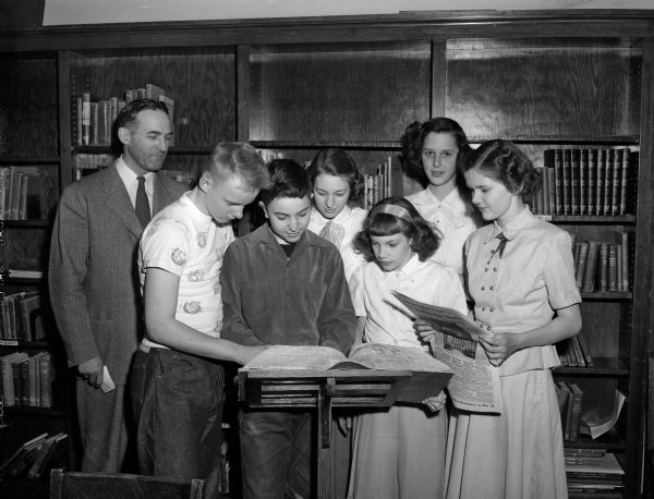 The six finalists in the recent Nakoma School contest to pick a champion for the city finals of the State Journal's Badger spelling bee look up misspelled words. They are shown with Principal Walter W. Engelke, smiling approval at the interest shown by his students.
They are, left to right: Engelke, Dick Hansen, Stuart Rosenfeld , Donna Wesenberg, Beth Knope, Joanne Leveque, and Mary Stuessy. Joanne Leveque won the spelling championship.