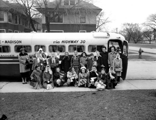 Twenty-one members of the Marquette School Girl Scout troop pose by a bus for a trip to Milwaukee.