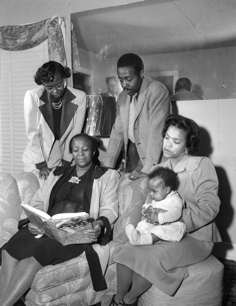 Mrs. Willie Lou Harris of 405 Bram Street sits at left with part of her family. Standing left to right are Mrs. James (Georgia Harris) Elvord, Mr. and Mrs. Calvin (Ruth) Harris, with their infant daughter, Charlene Elizabeth. Three other sons, Donald, Charles, and Richard, were not at home when the picture was taken. Mrs. Harris, whose grandfather was a slave, purchased eight building lots in South Madison in the middle of the Depression from her earnings as a domestic and hospital worker so that her five children could have homes of their own when they grew up.