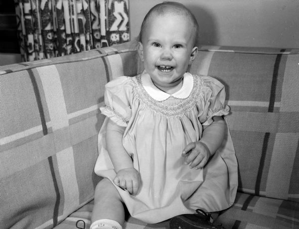 Margaret, age 11 months, sitting on a couch. She is the daughter of Dr. Lester and Elizabeth Antonius of 221 South Owen Drive. The portrait was taken as part of a collection of baby photos on the Society Page for observation of National Baby Week.
