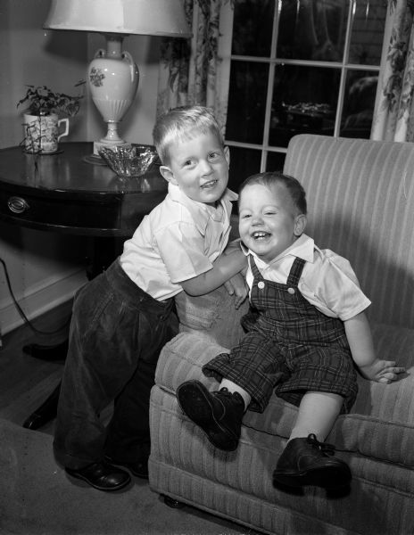 Robert, age three years, and Tommy, one year, sons of P. Goff and Mary Beach of 318 Woodland Circle, posing for a portrait in their living room. The photograph was one of a collection of baby photos on the Society Page for observation of National Baby Week.
