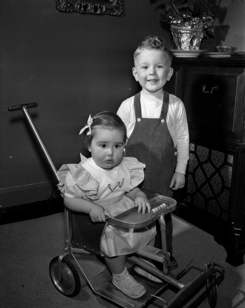 Ann, age 14 months, and Kenneth, three years, children of Dr. Kenneth and Kathleen Lemmer of 111 Virginia Terrace, posing for a portrait in their home. The photograph was one of a collection of baby photos on the Society Page for observation of National Baby Week.