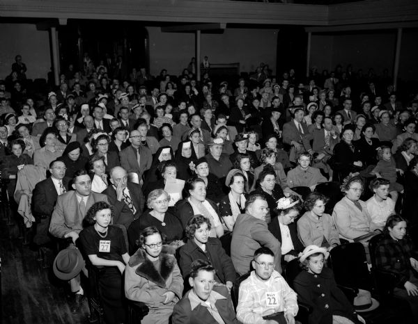 The audience at the Badger Spelling Bee audience, comprised of parents, teachers and students, sitting in an auditorium. The 1950 Badger Spelling Bee was sponsored by the <i>Wisconsin State Journal</i>.