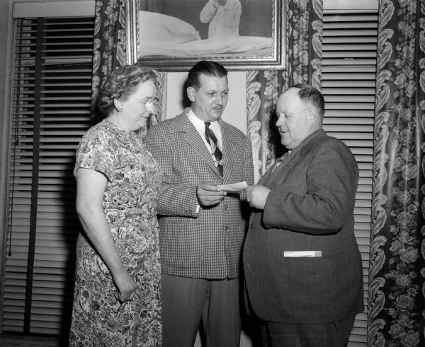 G.H. Showers, Moose Governor, offering a check to help members of the Boy Scouts Drum and Bugle Corp attend the National Scout Jamboree in Pennslyvania. Shown are Mrs. Jack Meier, representing the Moose Ladies' Auxiliary, and C.H. Beebe, director of the Four Lakes Council of Boy Scouts drum and bugle corps.