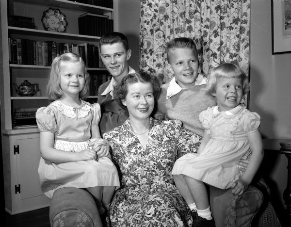 Mrs. Arnold H. (Margaret) Dammen, 4329 Hillcrest Drive, is pictured with her four children. Jane, age 5, sits at left next to her mother, and Mary Kate, 4, sits to her mother's right. Standing behind their mother and sisters are James, 18, at left, and David, 13.