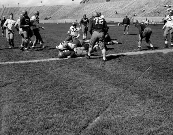 Darel "The Bull" Teteak (#44) is shown face down on the field at Camp Randal Stadium with Bob Radcliffe (#33), Dave Stalger (#72) and Bobby Petruska (#24).