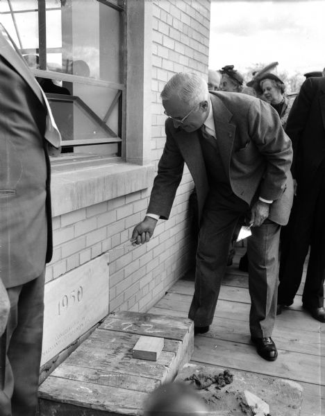 President Harry S. Truman visited Madison to be present at the laying of the cornerstone for the CUNA's Filene House, 1617 Sherman Avenue.  He is pictured with a trowel as he bends toward the cornerstone.