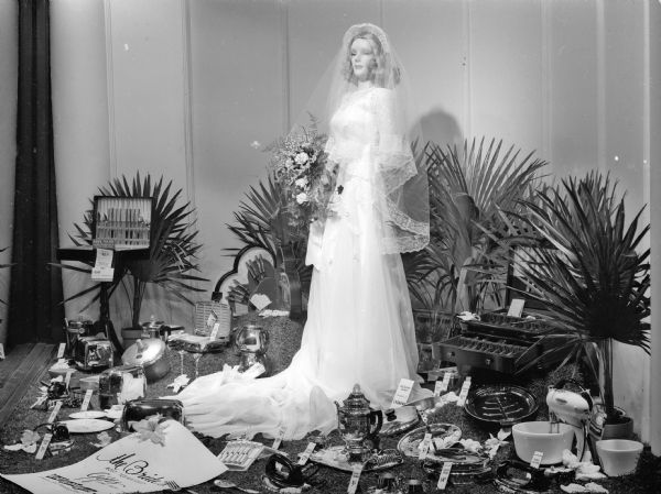 Display window featuring a mannequin in a bridal gown and household items at Wolff Kubly Hirsig Hardware Store, 17 South Pinckney Street.