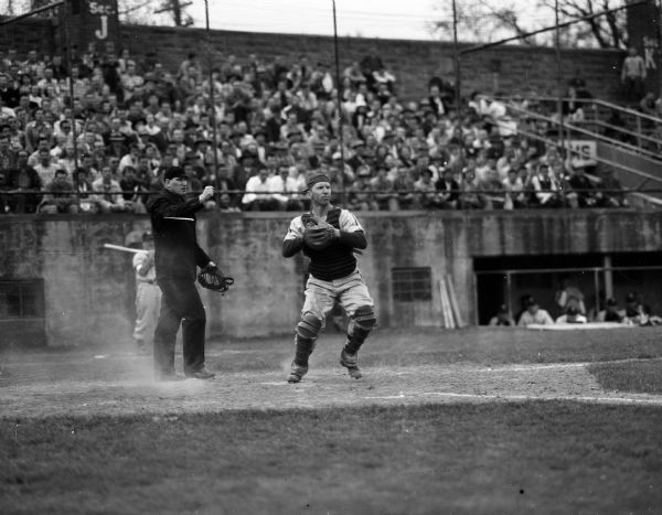 Catcher Robert "Red" Wilson stands ready to throw to Bob Shea during the completion of a double play during a baseball game between the University of Wisconsin and the University of Michigan.