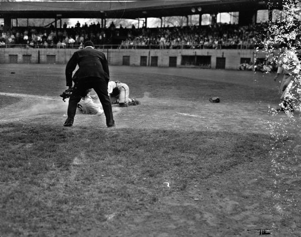 Catcher Robert "Red" Wilson of the University of Wisconsin puts the double play ending tag on Bill Bucholz of the University of Michigan.