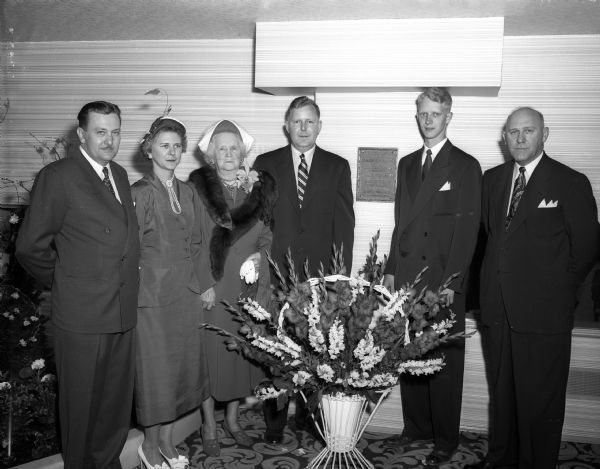 Edgewater Hotel dedicated to Madison contractor and civic leader John H. Findorff, builder of the hotel.  Dedication is marked with a bronze plaque hanging at the hotel entrance.  Pictured from left to right are: Dr. A.A. Quisling, president of the Edgewater Corp.; Arline Findorff, daughter of Mr. Findorff, Carol Findorff, Mr. Findorff's widow, John R. and Gordon Findorff, who hung the plaque, and Milton B. Findorff, M.r Findorff's son.