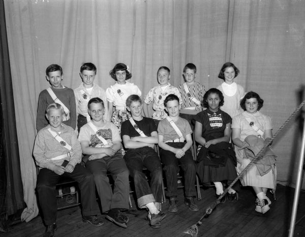 Madison school safety patrol captains honored at an appreciation show posing for a group portrait. In the front row are, left to right: Roger Schwarze, James Stieve, Richard Ragatz, Jerry Rose, Arlene Taylor, and Phyllis Kepler. In the back row, left to right, are Donald Hackburt, Gary Gillette, Lois Lintner, Dave Bickel, James Piper, and Jean Dammann.