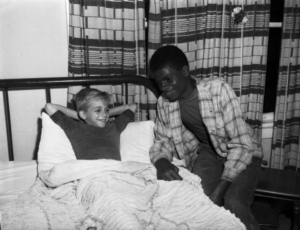 Charles Hargrove, age 12, sitting at the bedside of Robert Byrnes, age 9, after Charles pulled Robert from Murphy Creek on Madison's south side. The boys had gone fishing and Robert fell into the deep water.